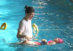 Instructor teaching a child how to float 